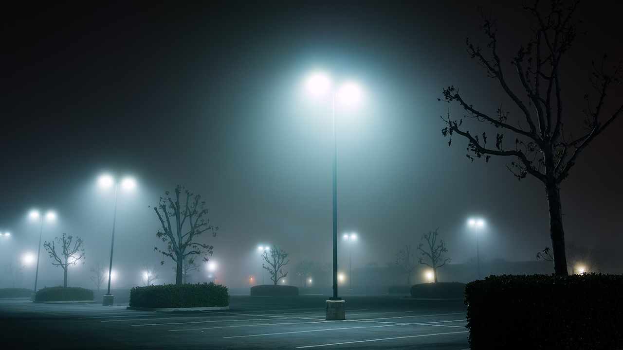 Beleuchteter Parkplatz bei naechtlichem Nebel